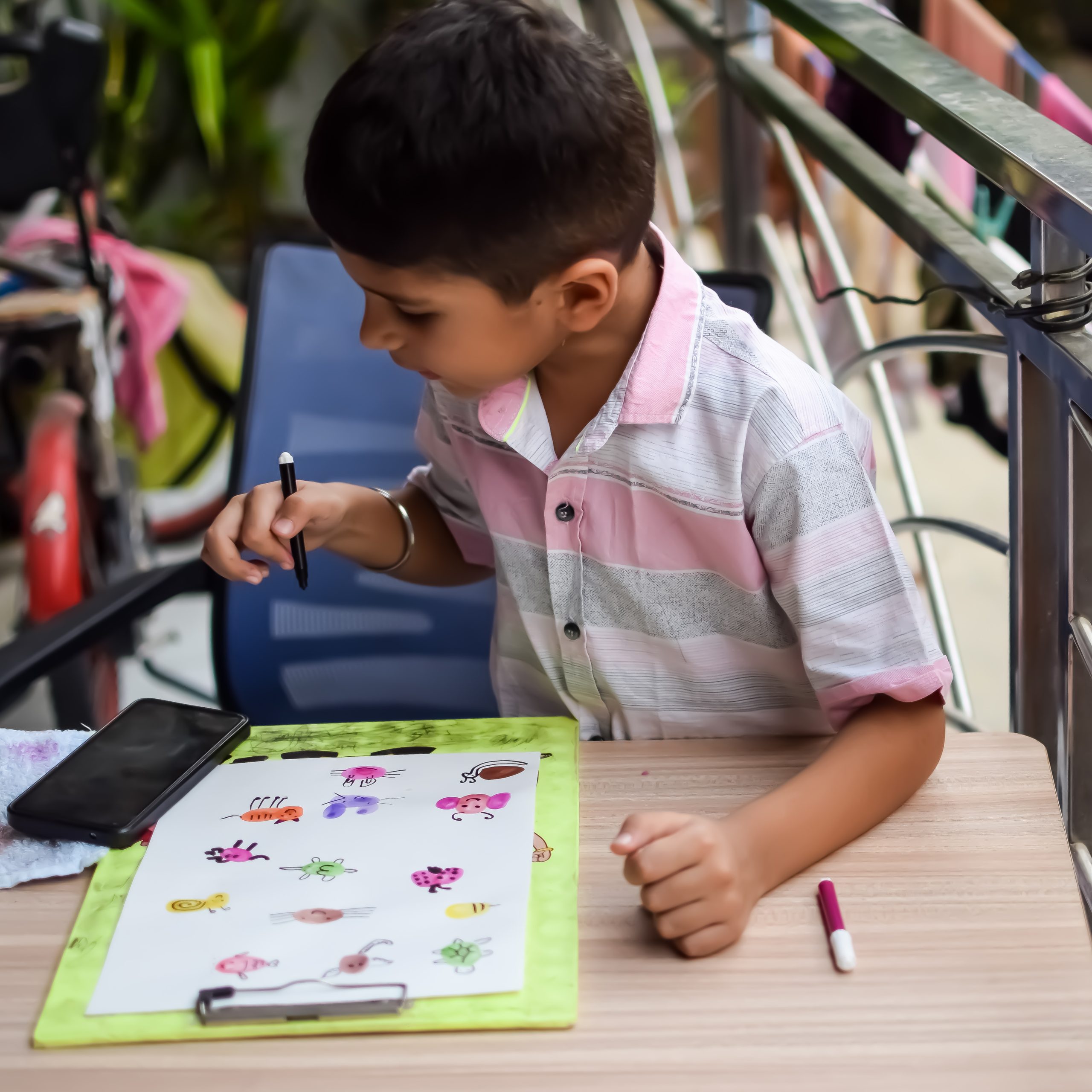 Smart Indian little boy perform thumb painting with different colourful water colour kit during the summer vacations, Cute Indian Kid doing colourful thumb painting drawing on wooden table Smart Indian little boy perform thumb painting with different colourful water colour kit during the summer vacations, Cute Indian Kid doing colourful thumb painting drawing on wooden table